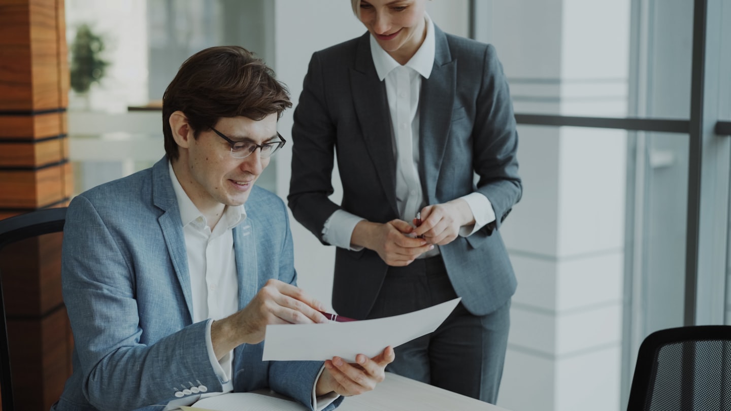 Man and woman collaborating over documents in a modern office.