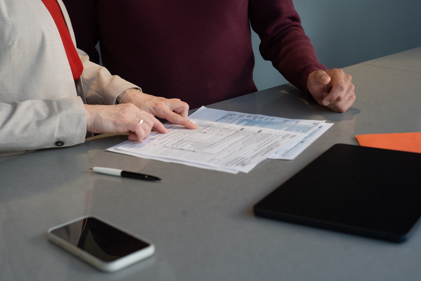 Two people reviewing financial documents at a desk.